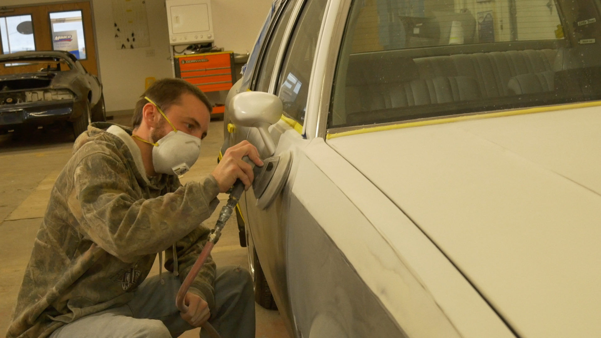 Repair mechanic sanding the side of a vehicle at Flower City Collision